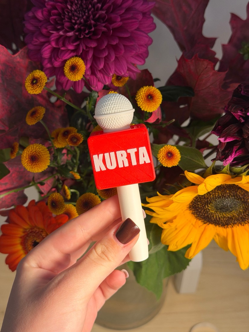 Červený mikrofon s nápisem KURTA v ruce
